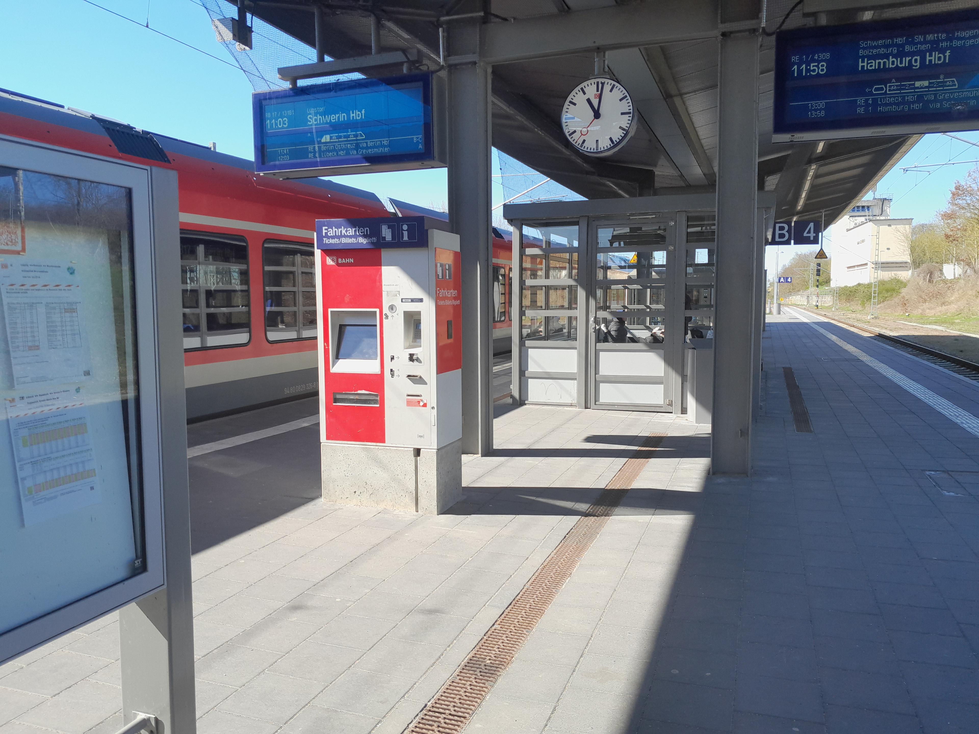 Blick auf den Bahnsteig Gleis 3/4, mit alter Uhr, alten Informationsmonitoren unter dem Bahnsteigdach und einer Vitrine mit Papieraushängen für die Wagenreihung der Züge.  